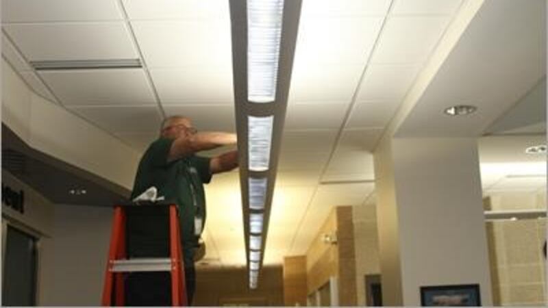 A City of Wilmington worker switches a fluorescent bulb for a more energy efficient LED bulb.