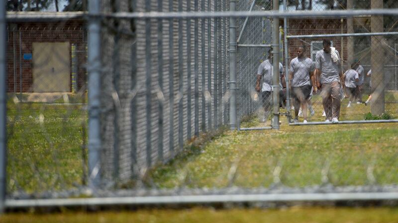 Inmates at Neuse Correctional Institution walk outside behind fences in Goldsboro on May 15,...