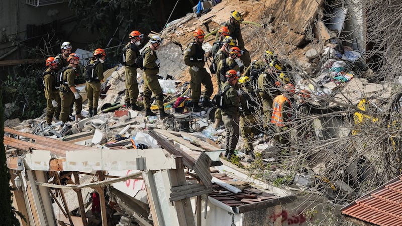 Israeli rescue teams search for missing people amid the rubble of a residential building a day...